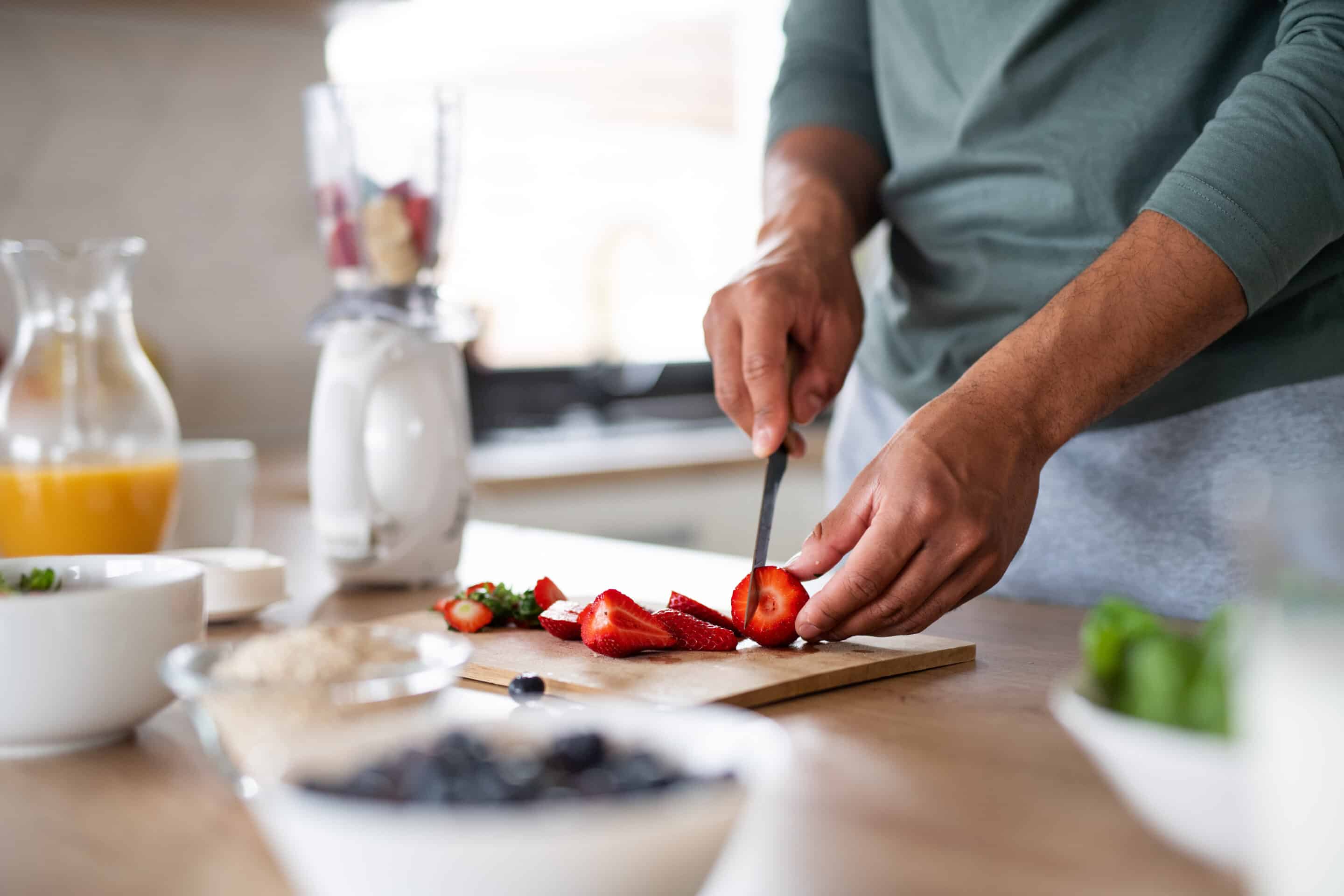 Männliche Hände bereiten ein gesundes Essen vor: Erdbeeren und Ost